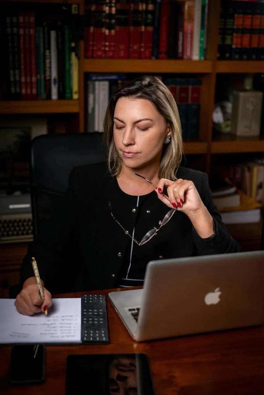 Rafaela Chaves anotando em uma agenda ao lado do notebook, na biblioteca
